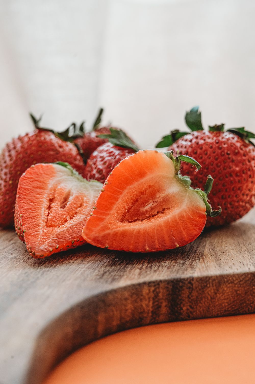 Fresh ripe strawberries cut in half showing vibrant red interior on wooden cutting board. SIX84 Photography, Food Photography, Sydney