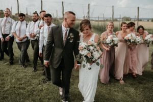 Bride and groom and wedding party walking towards the camera with seneca lake behind them