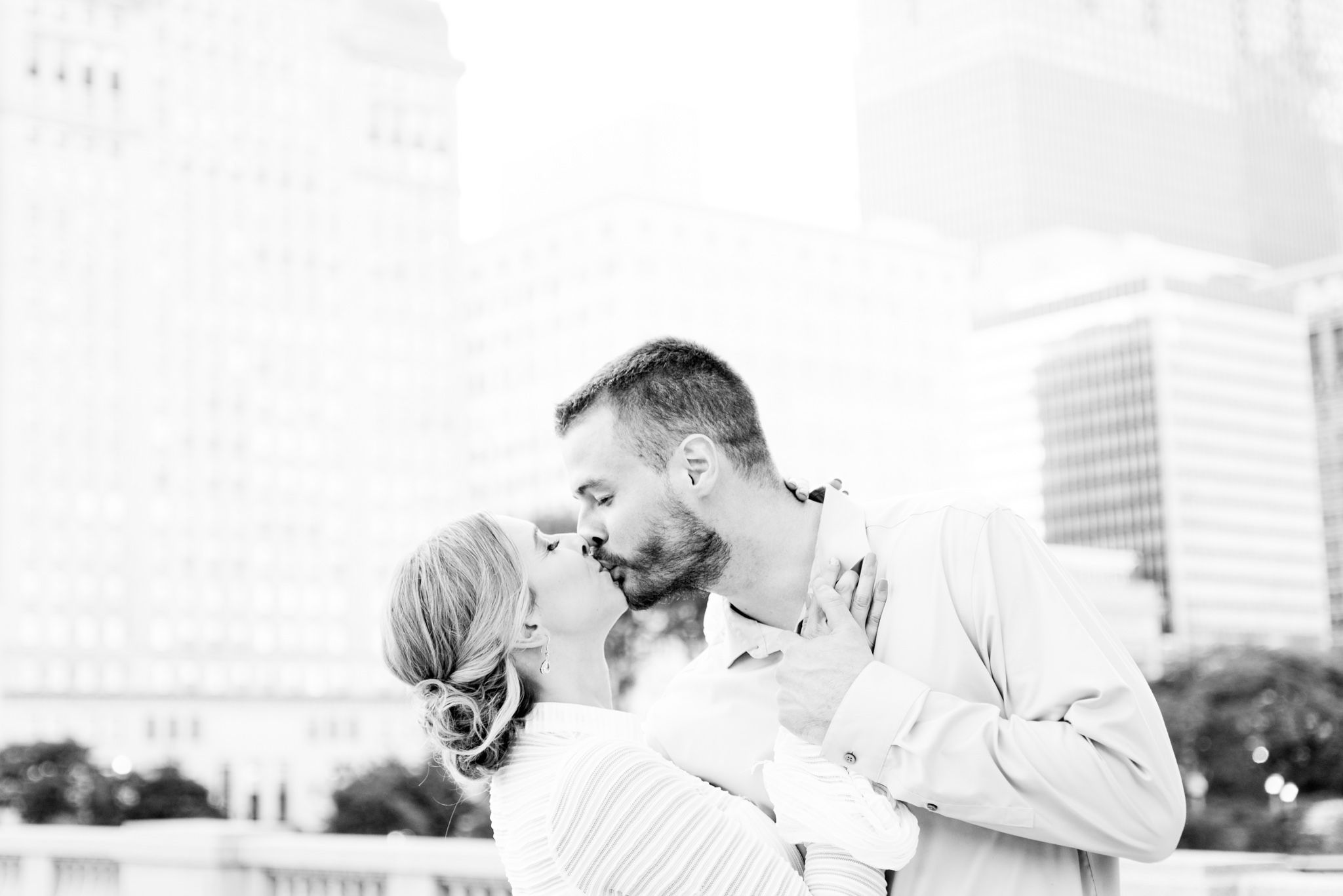 engaged man and woman kiss in front of Chicago skyline at downtown Chicago engagement pictures