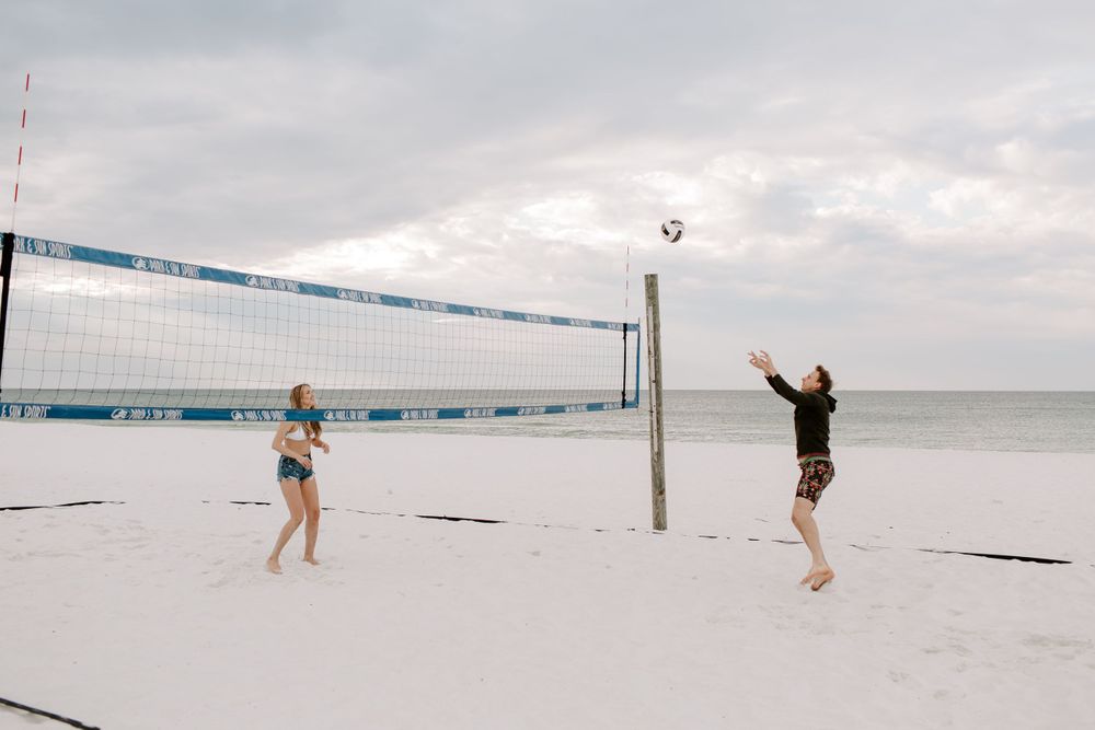 couple playing volleyball on Okaloosa Island during their engagement sessin