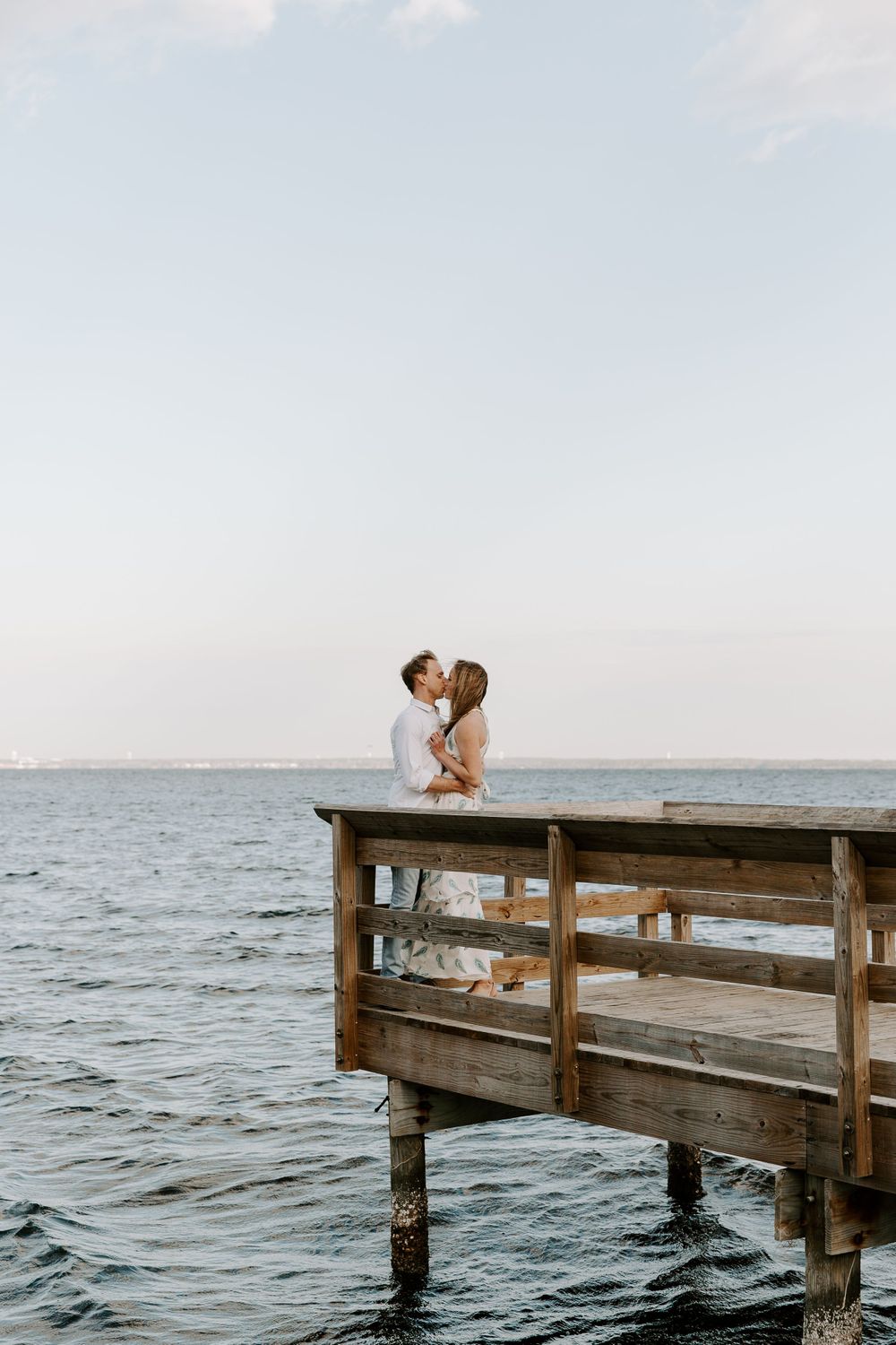 couple standing at the end of a pair facing each other sharing a kiss during their Florida engagement session