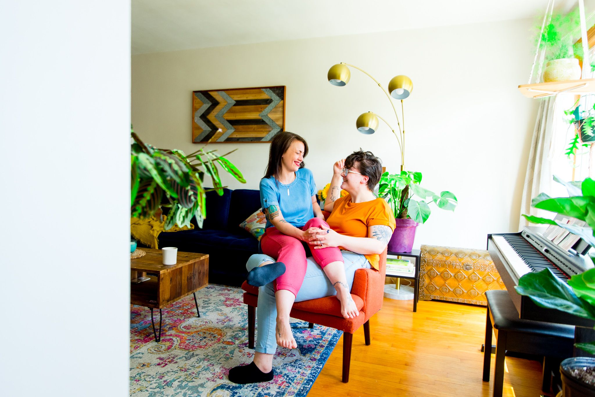 lesbian couple sitting in orange chair together in their Chicago living room anniversary pictures