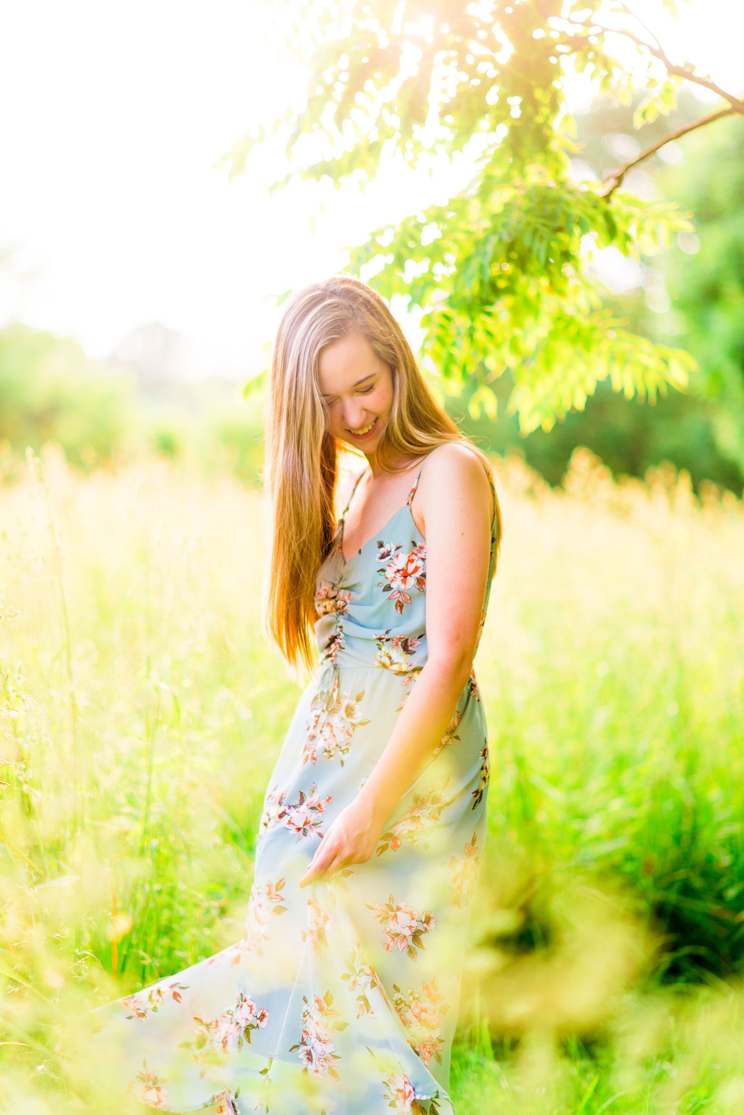 high school girl in blue floral dress dancing in field of tall grass at sunset at Montrose Harbor Chicago