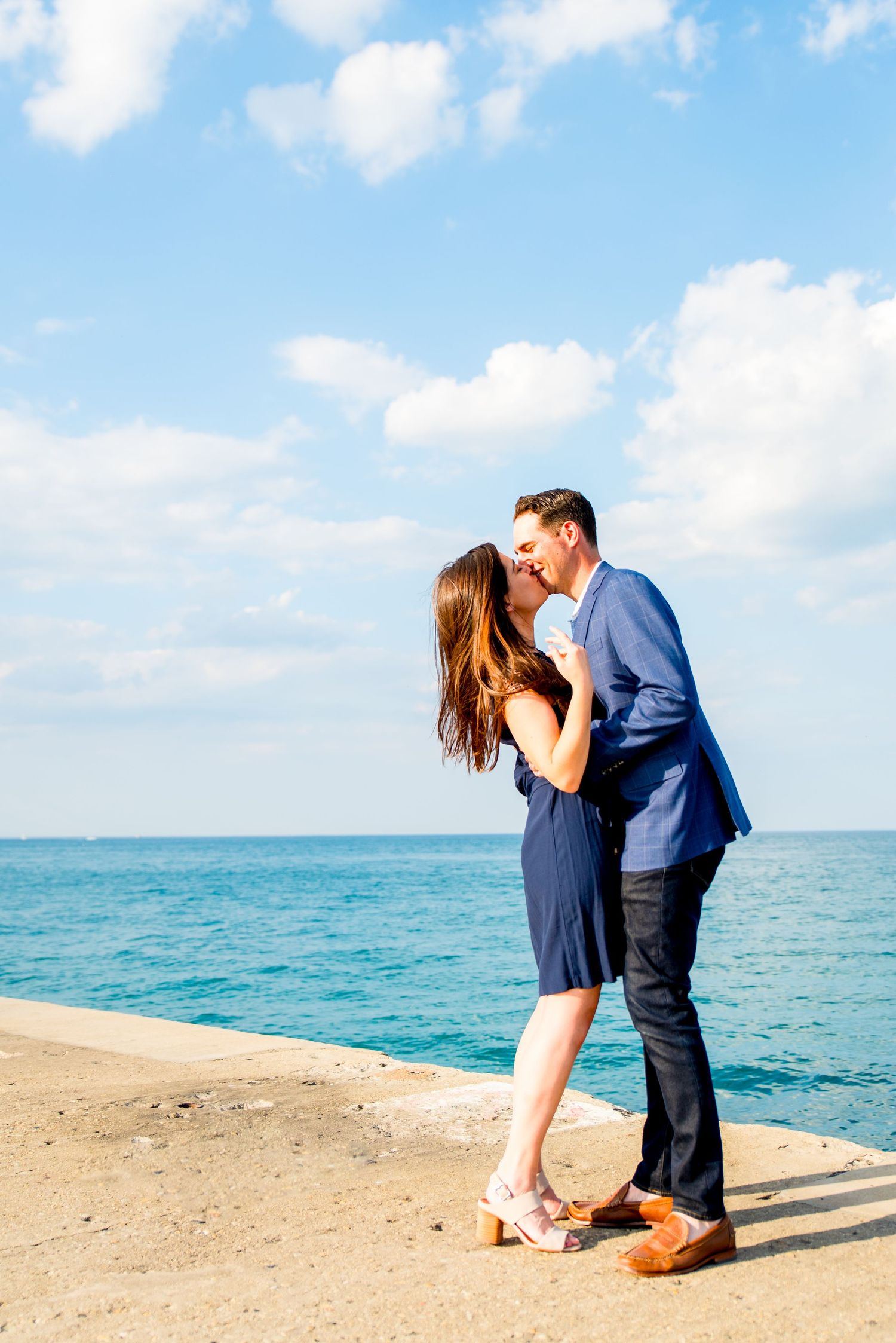 man and woman in navy blue kissing at North Avenue Beach pier during sunset proposal