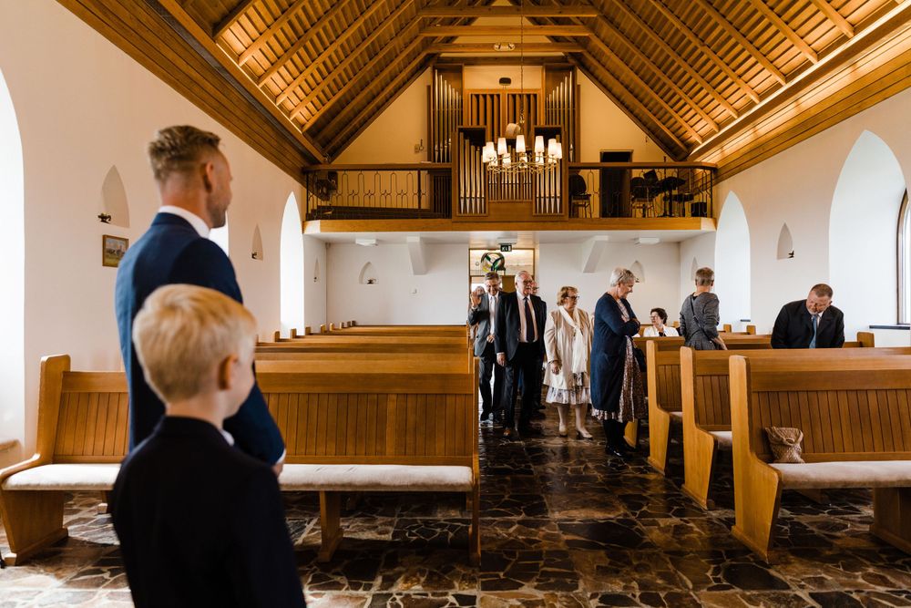 Interior of a traditional church with vaulted ceiling and wooden pews during a wedding ceremony.
