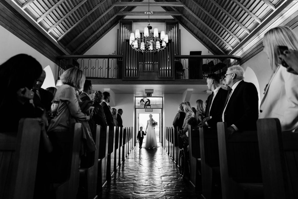 Black and white photo of a church wedding ceremony with dramatic lighting and an organ pipe backdrop.