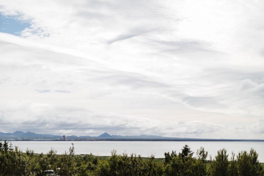 Scenic mountain landscape with calm water and cloudy sky in the distance.