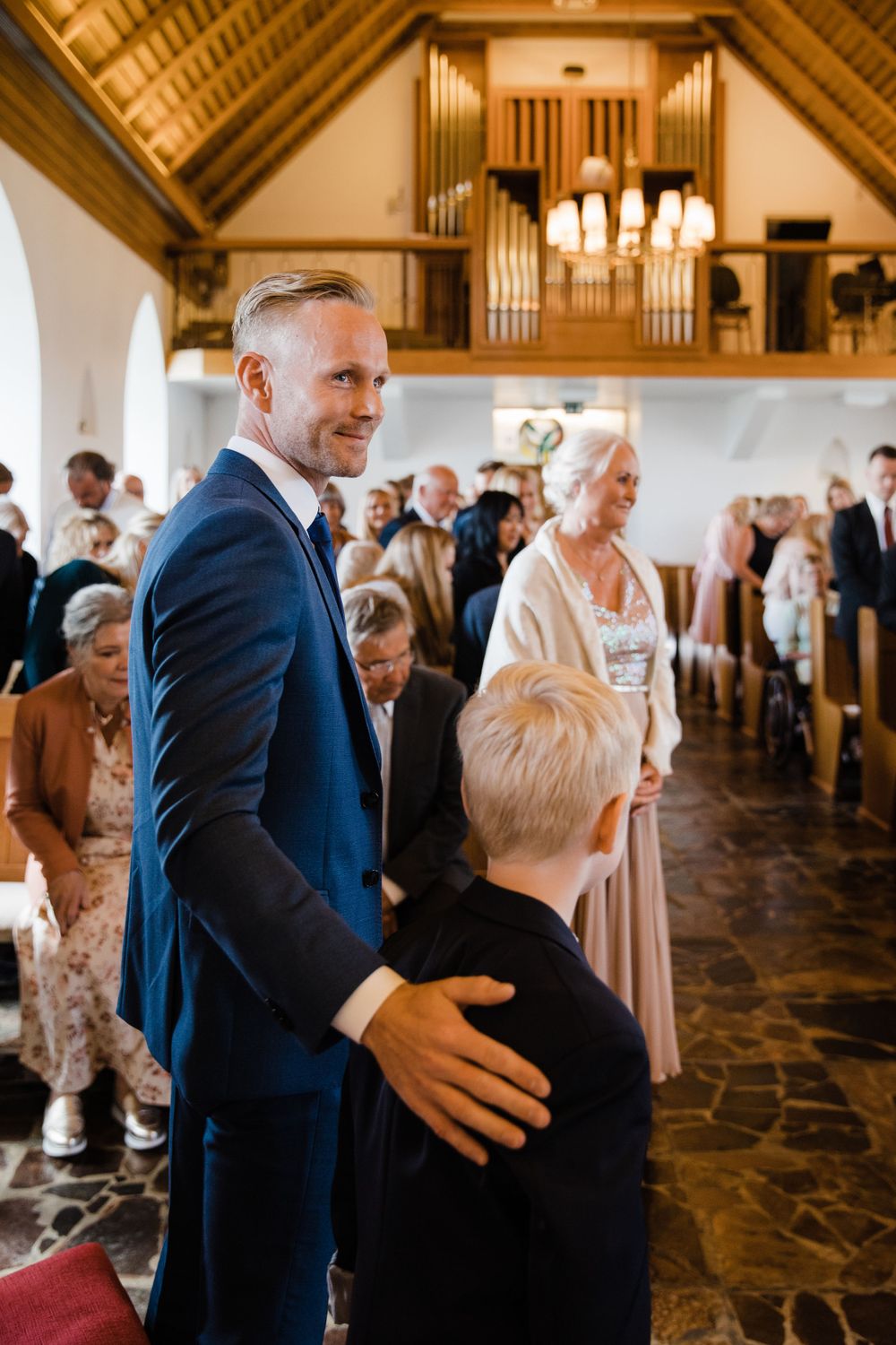 A tender moment during a church wedding ceremony showing guests gathered in a beautiful chapel with vaulted ceilings.