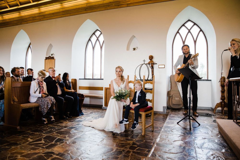 A wedding ceremony in progress inside a charming chapel with Gothic windows and stone flooring.