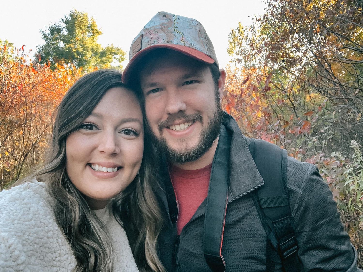 Outdoor autumn selfie with fall foliage in the background.