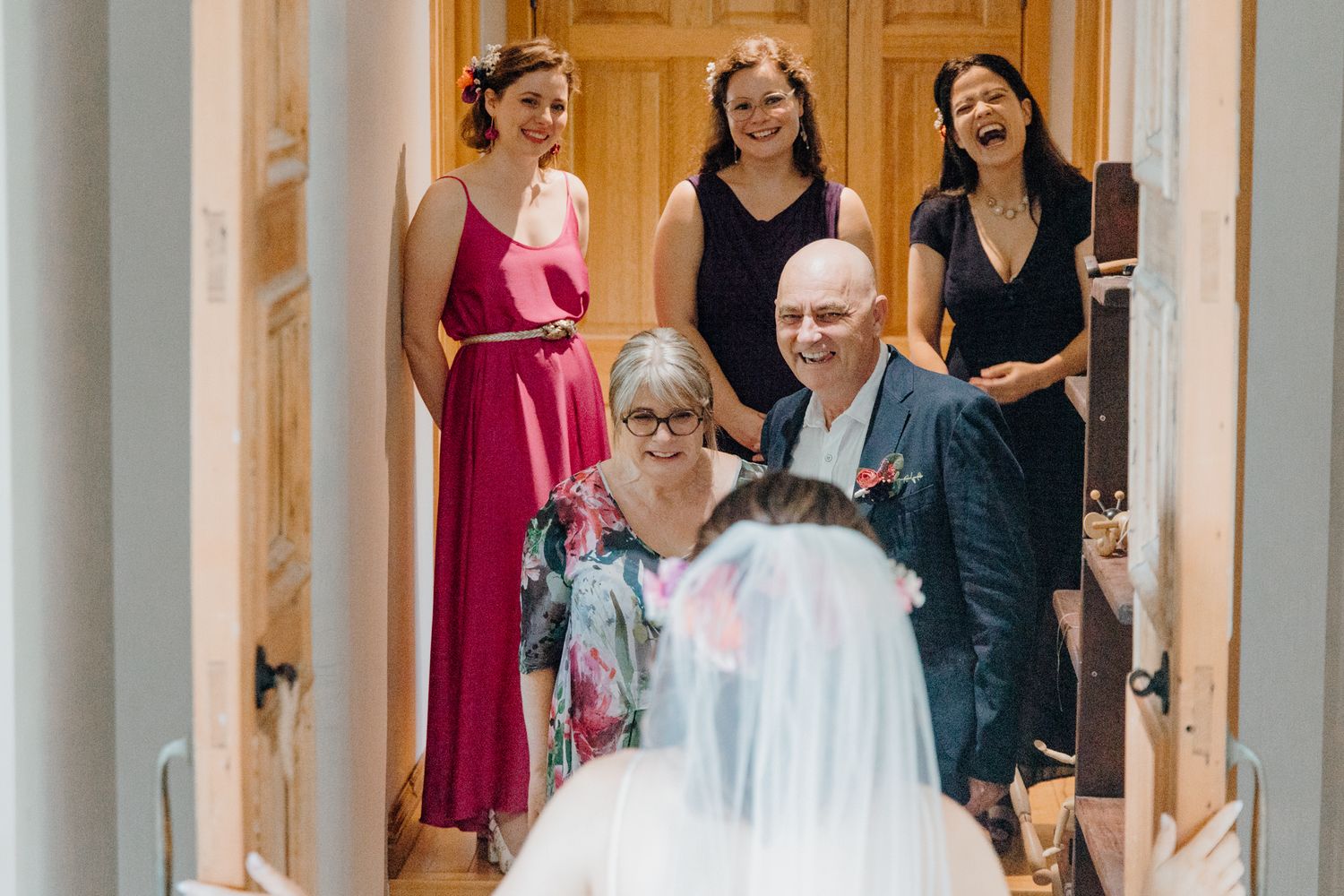 A joyful group gathered in a hallway during wedding preparations.