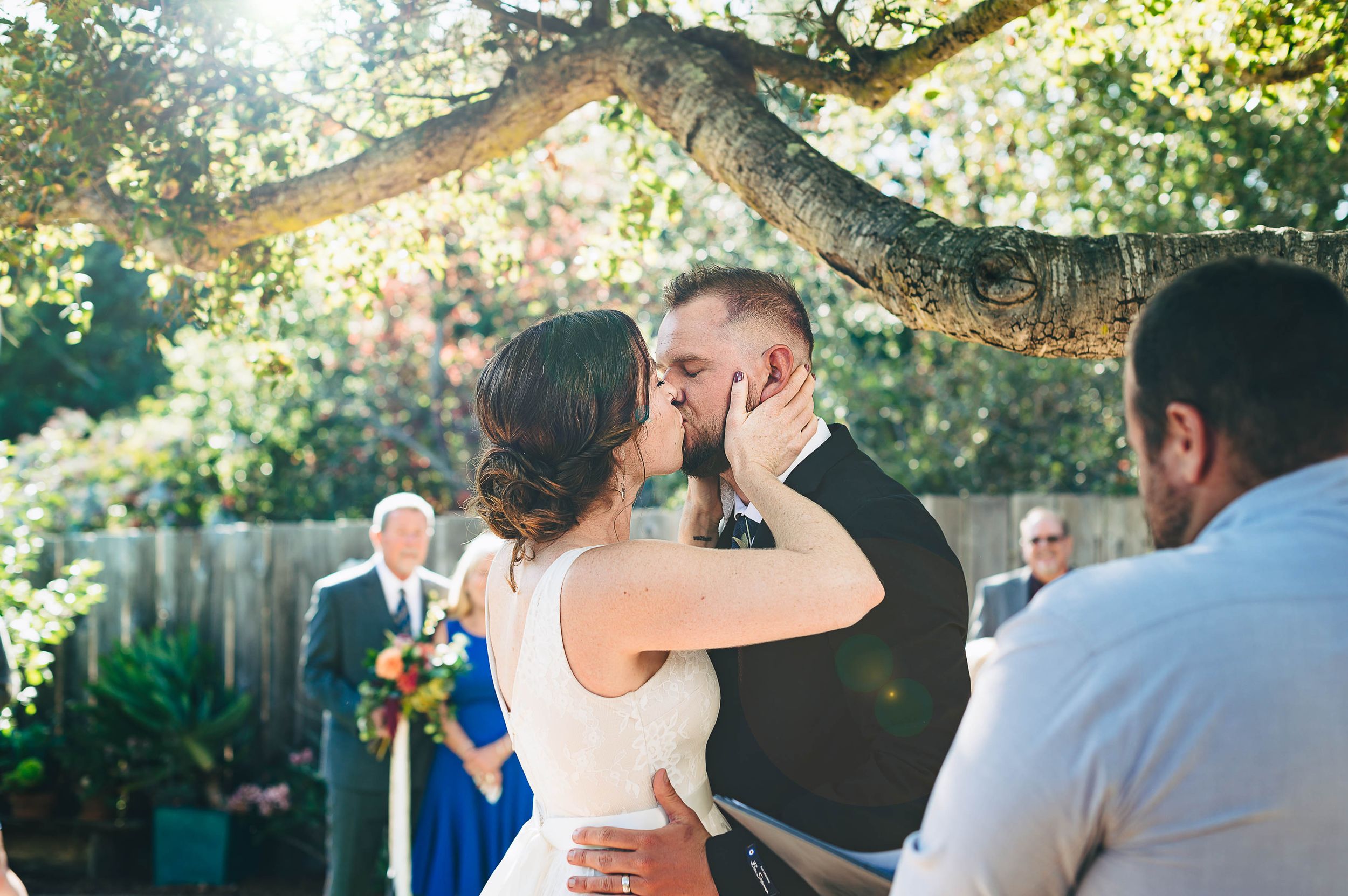 Bride and groom having their first kiss at their intimate backyard wedding ceremony in Santa Cruz
