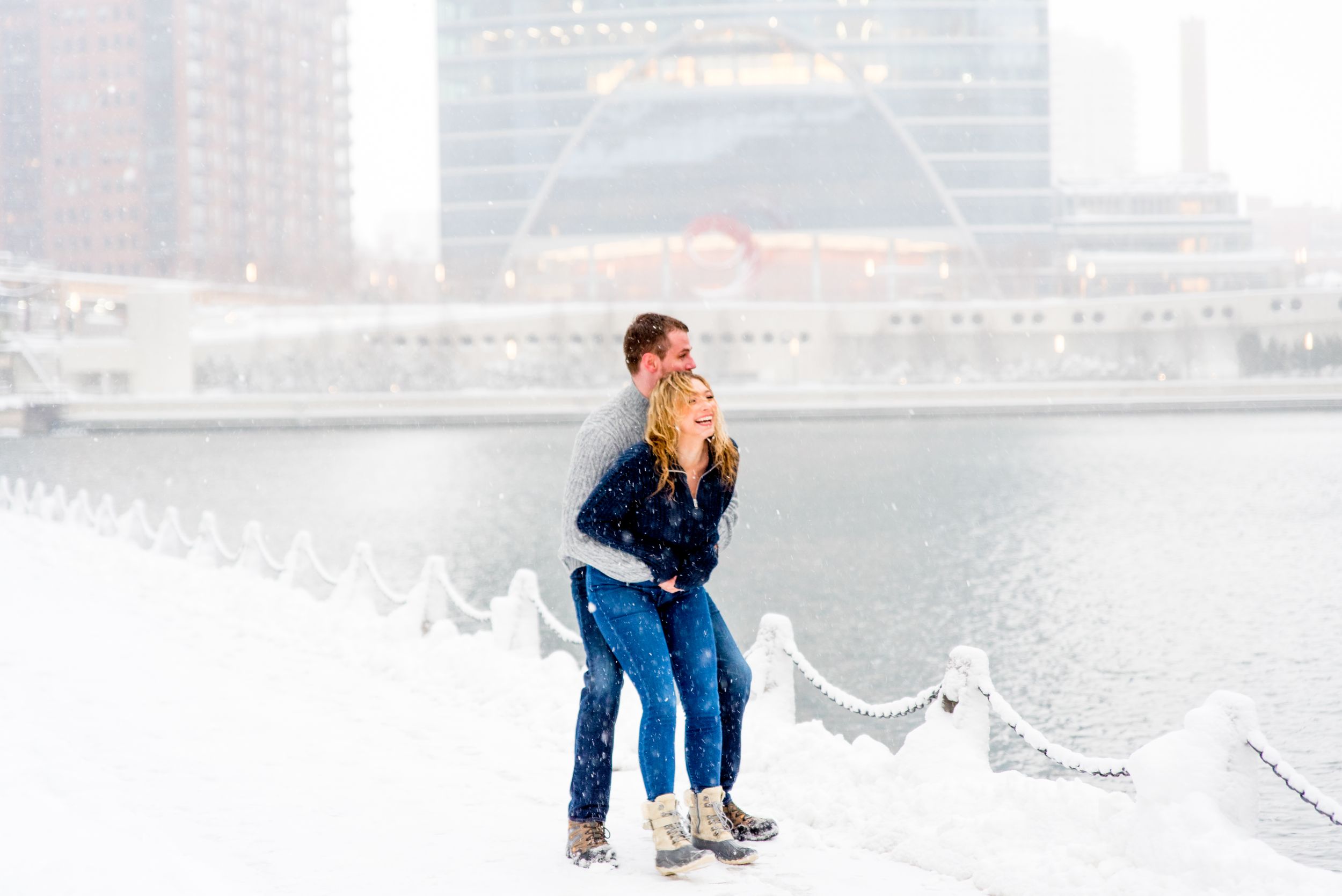 man and woman in navy and grey sweaters smiling in snow at Merchandise Mart