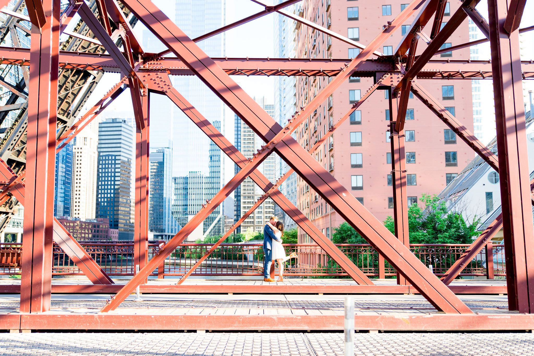engaged man and woman kissing in the middle of Kinzie St Bridge for Chicago sunset engagement pictures