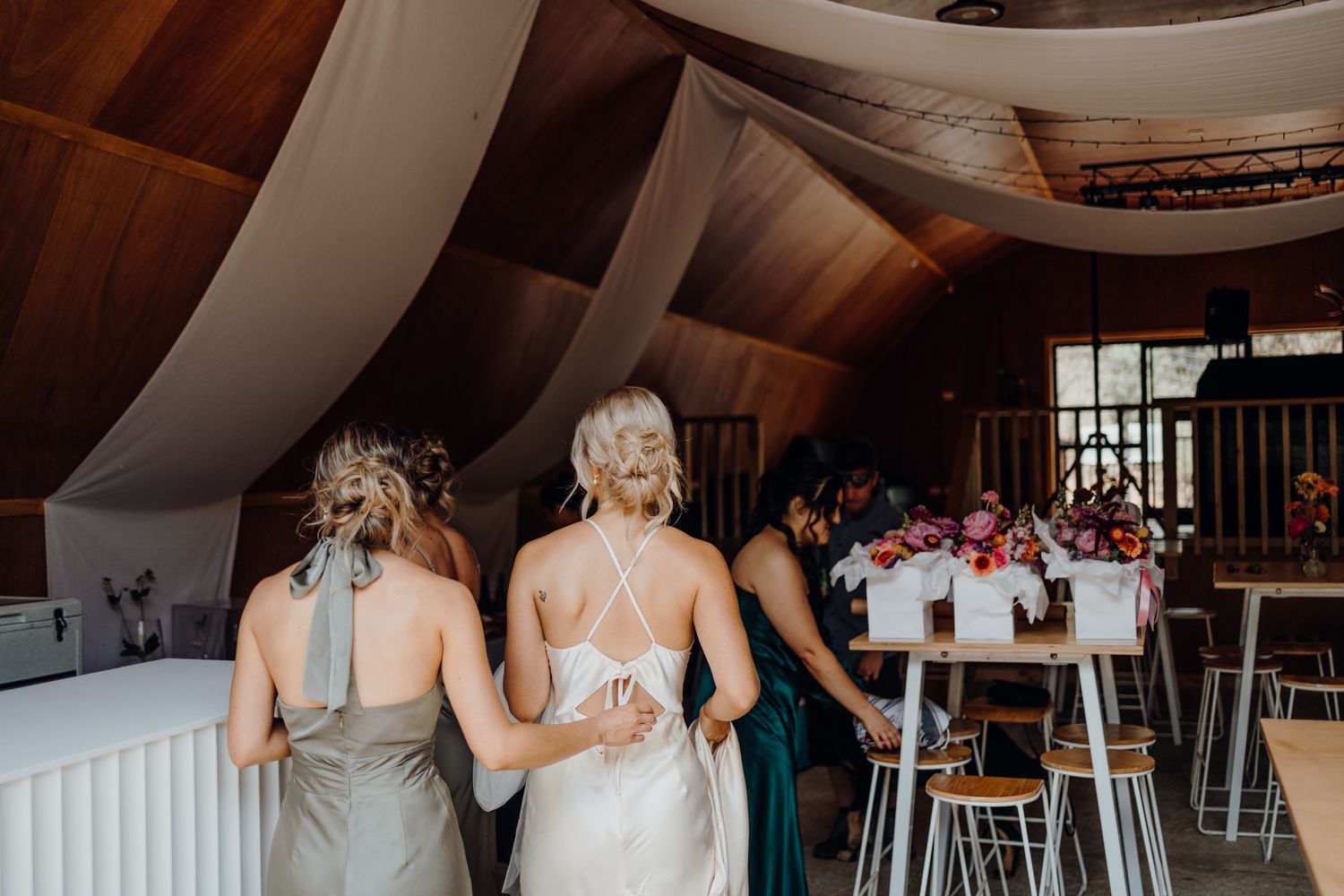Wedding celebration in a rustic venue with draped fabric ceiling and wooden bar setup.