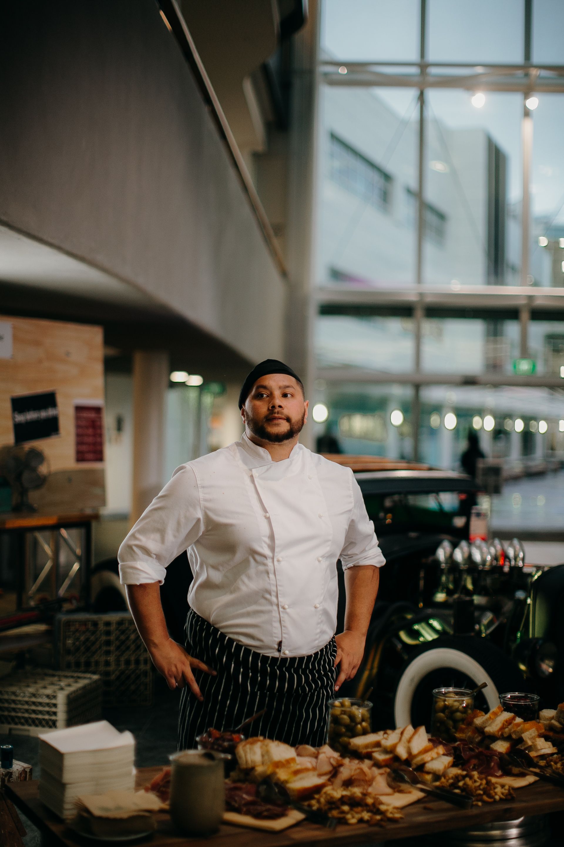 chef stands proudly behind table of prepared food