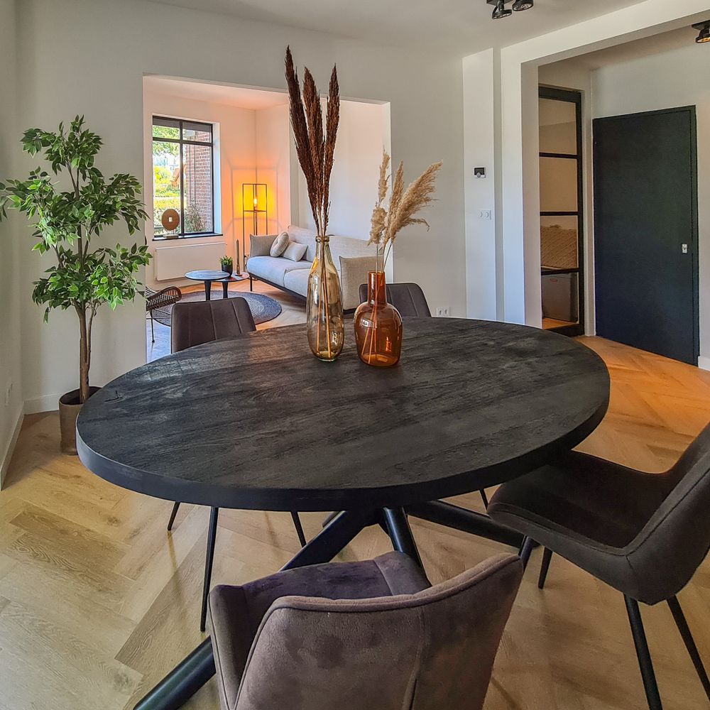 Ronde eettafel met vier stoelen en decoratieve vazen met pluimen