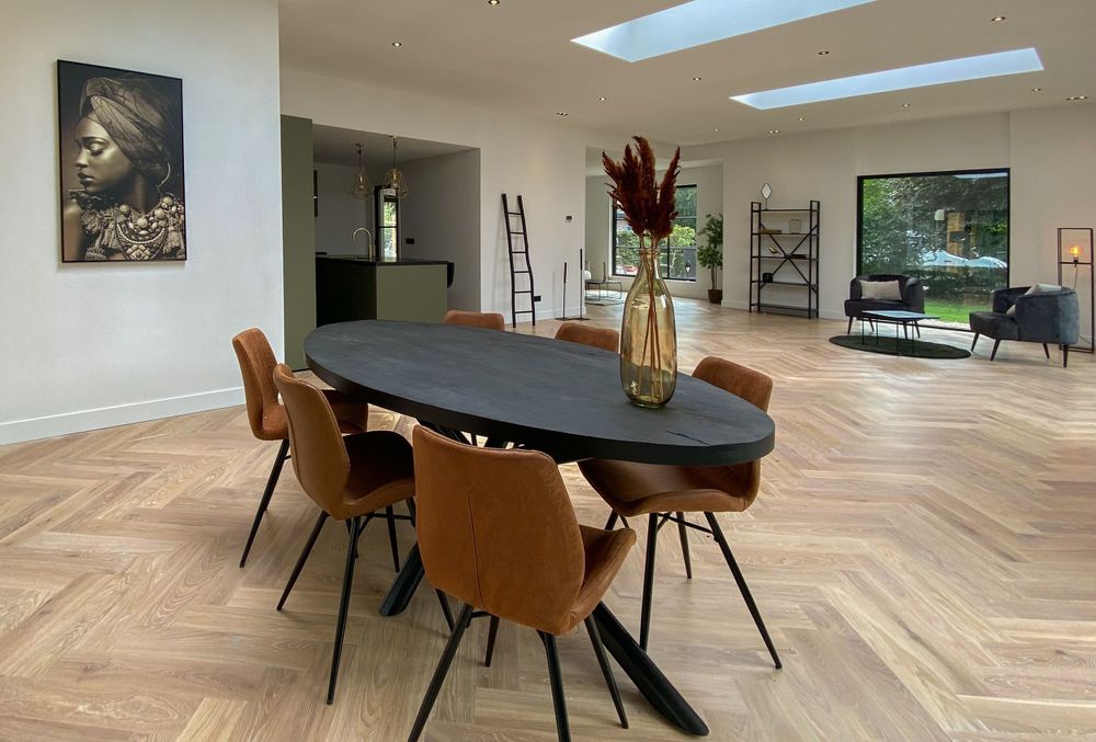 Ovale eettafel met zes stoelen en op de achtergrond een zithoek met wandkast