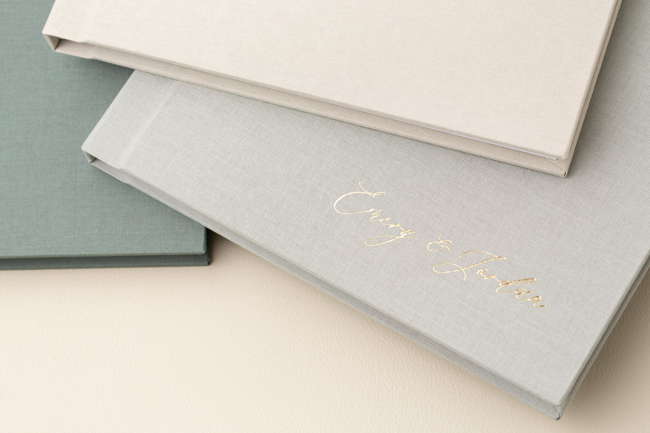 Elegant photo albums with gold text stacked on neutral background.