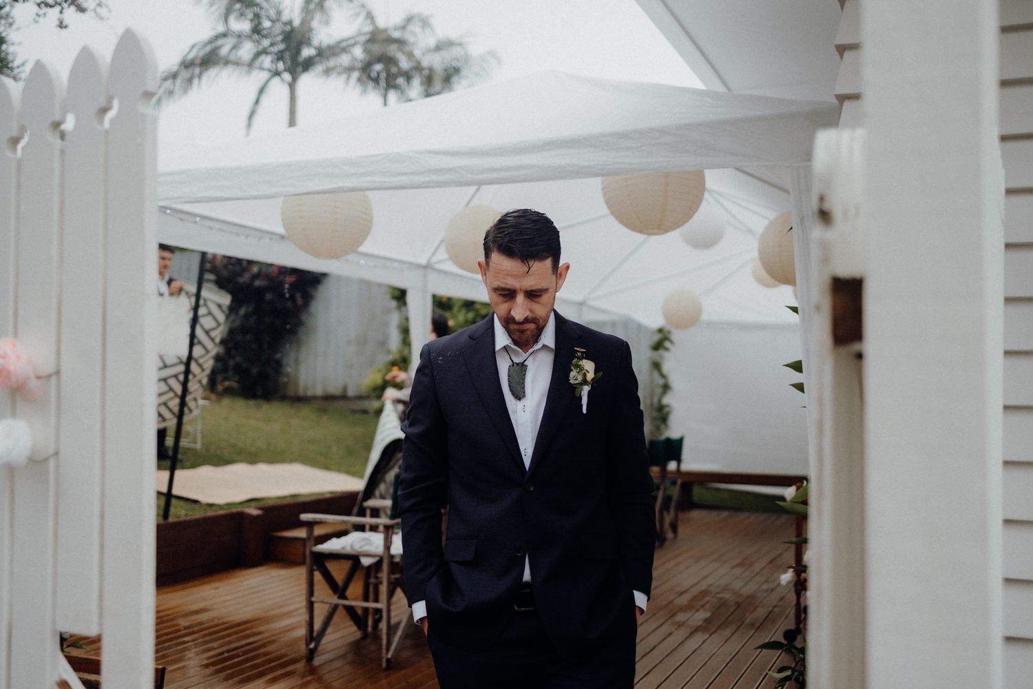 A wedding ceremony setup under a white tent with hanging paper lanterns and wooden deck.