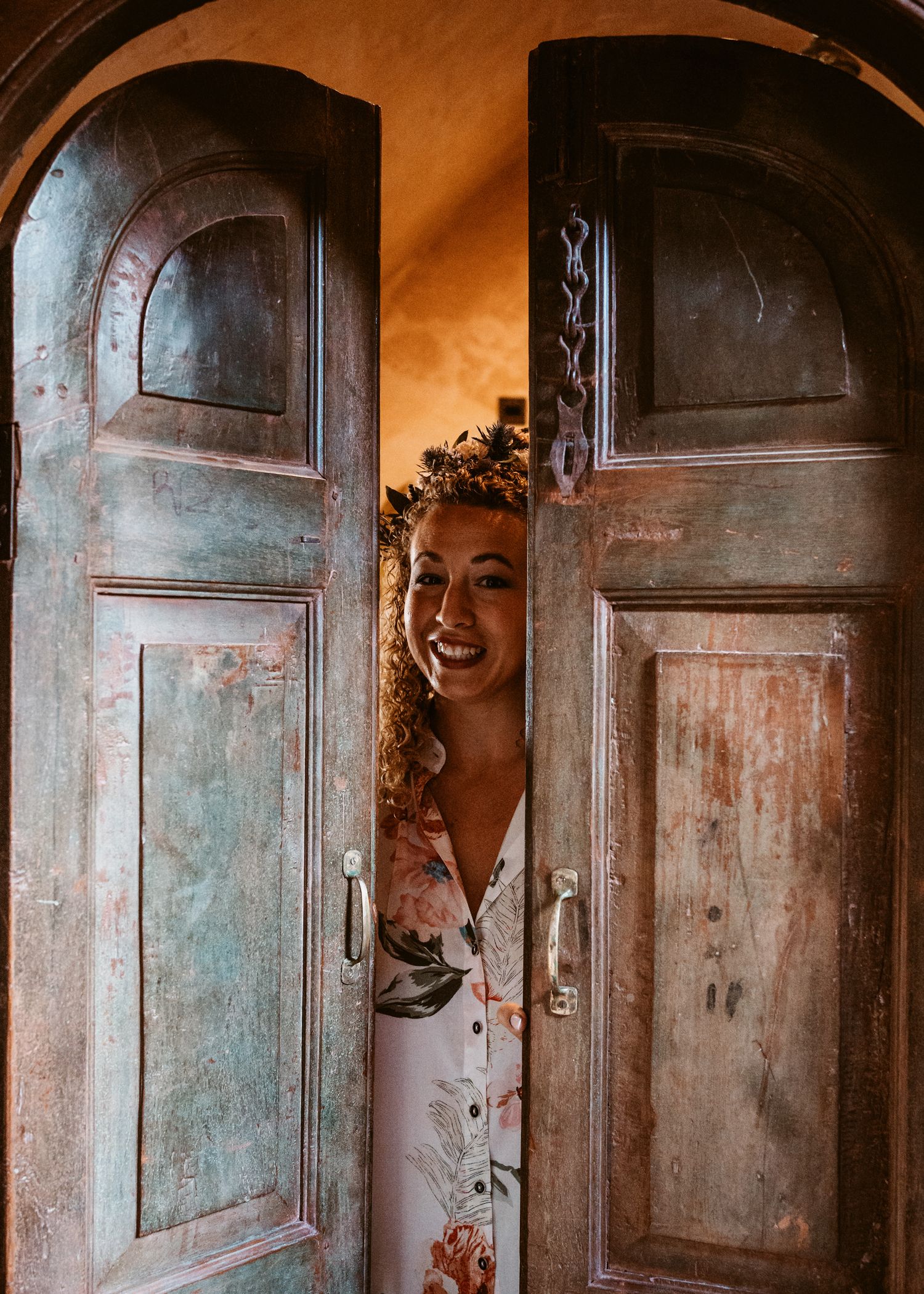 bride peeping through arched doors of rustic styled, quirky wedding preparations accommodation