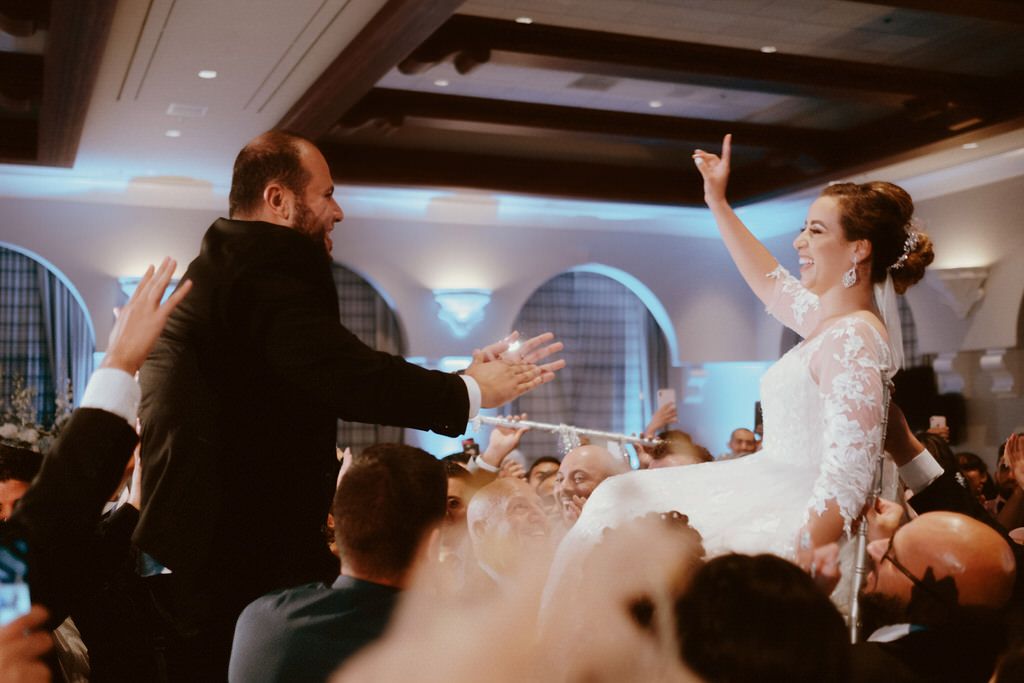 A joyous celebration unfolds on a wedding dance floor with party guests enjoying the festivities.