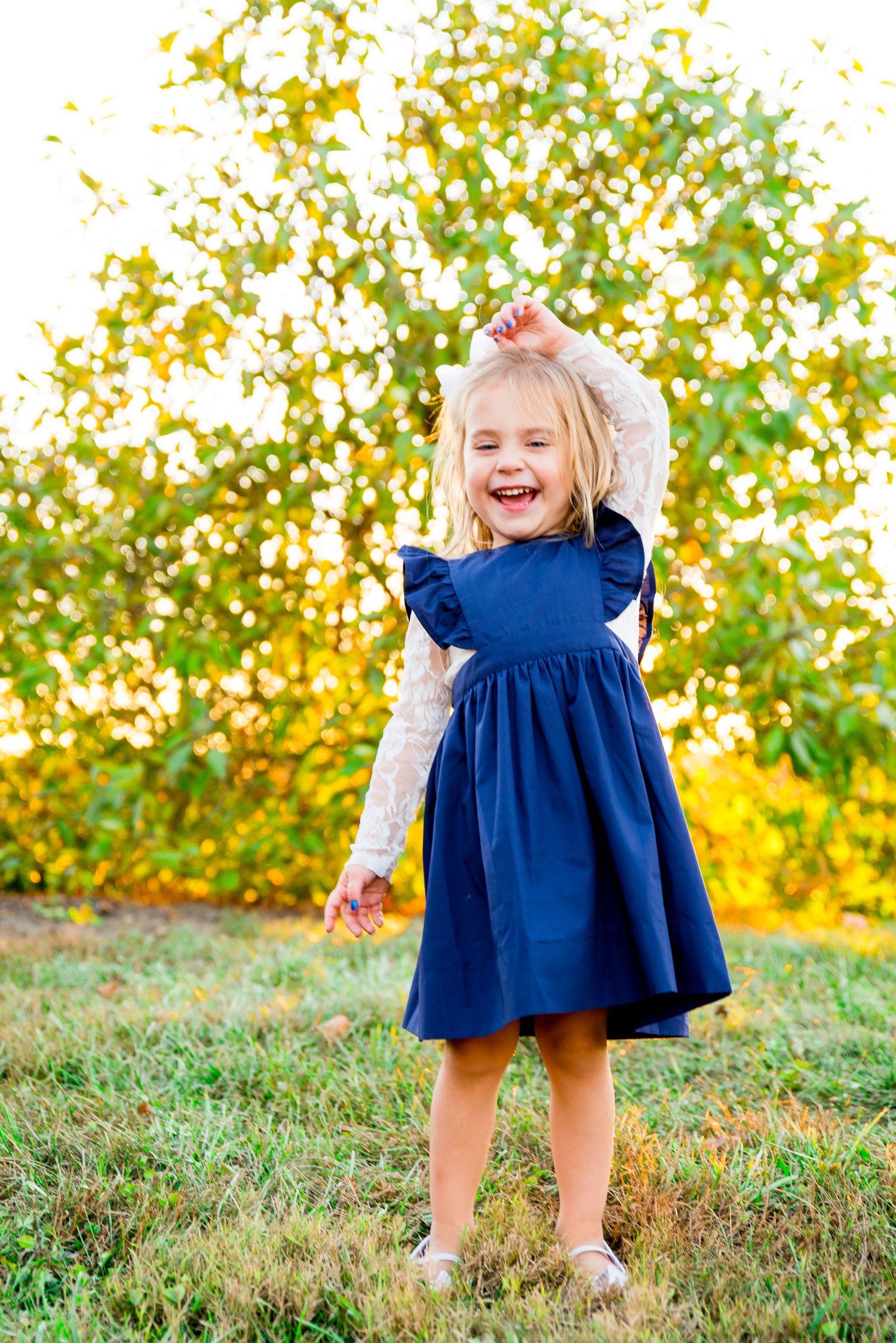 young blonde girl in navy dress and white long sleeves dancing at sunset in Grant Park