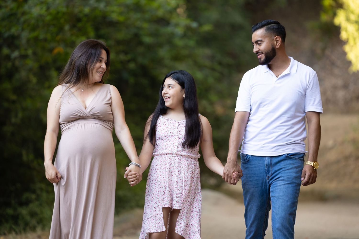 mother, daughter, and father holding hands while smiling