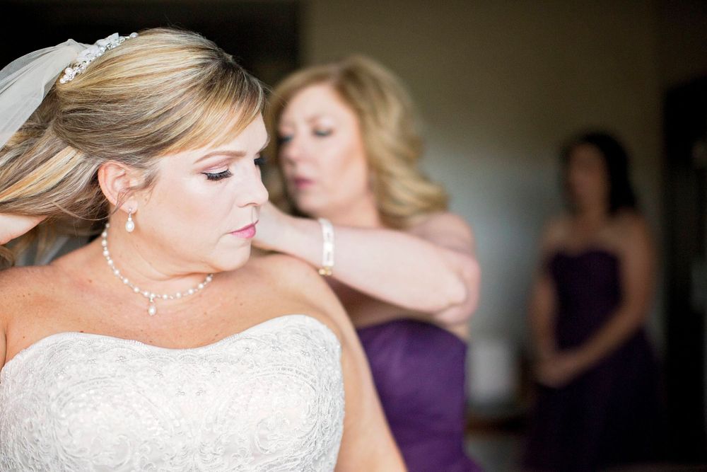 bridesmaid helping bride put on necklace at Allegretto Vineyard Resort