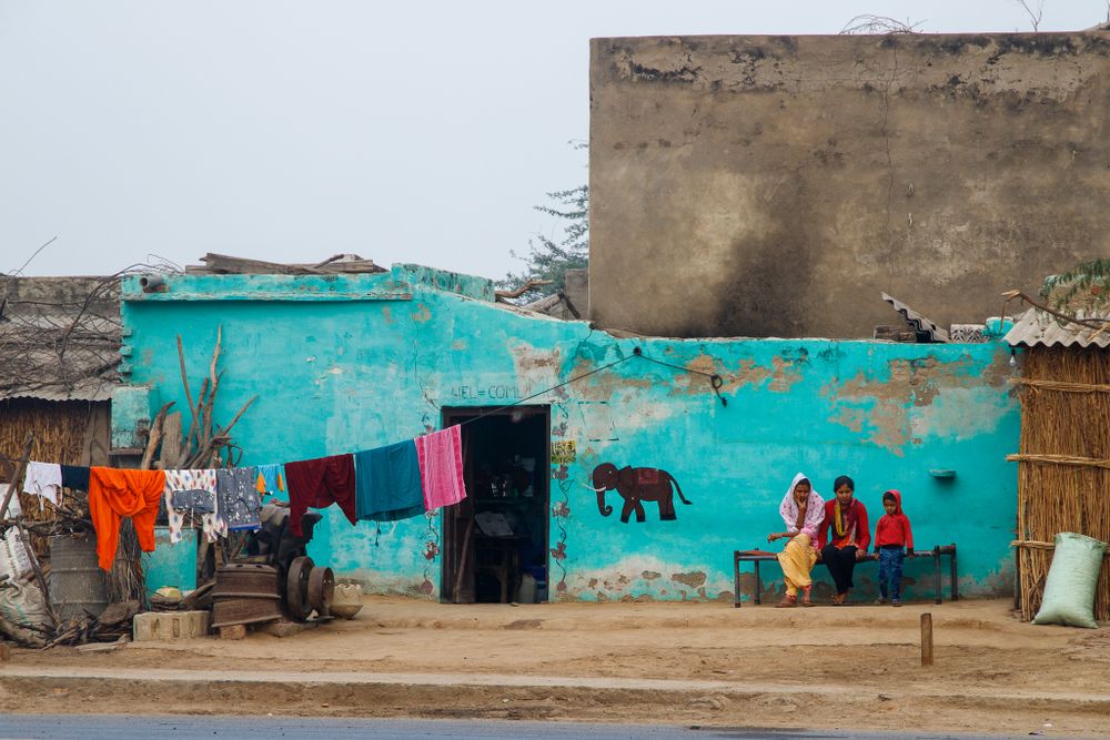 young family sitting outside colourful home India