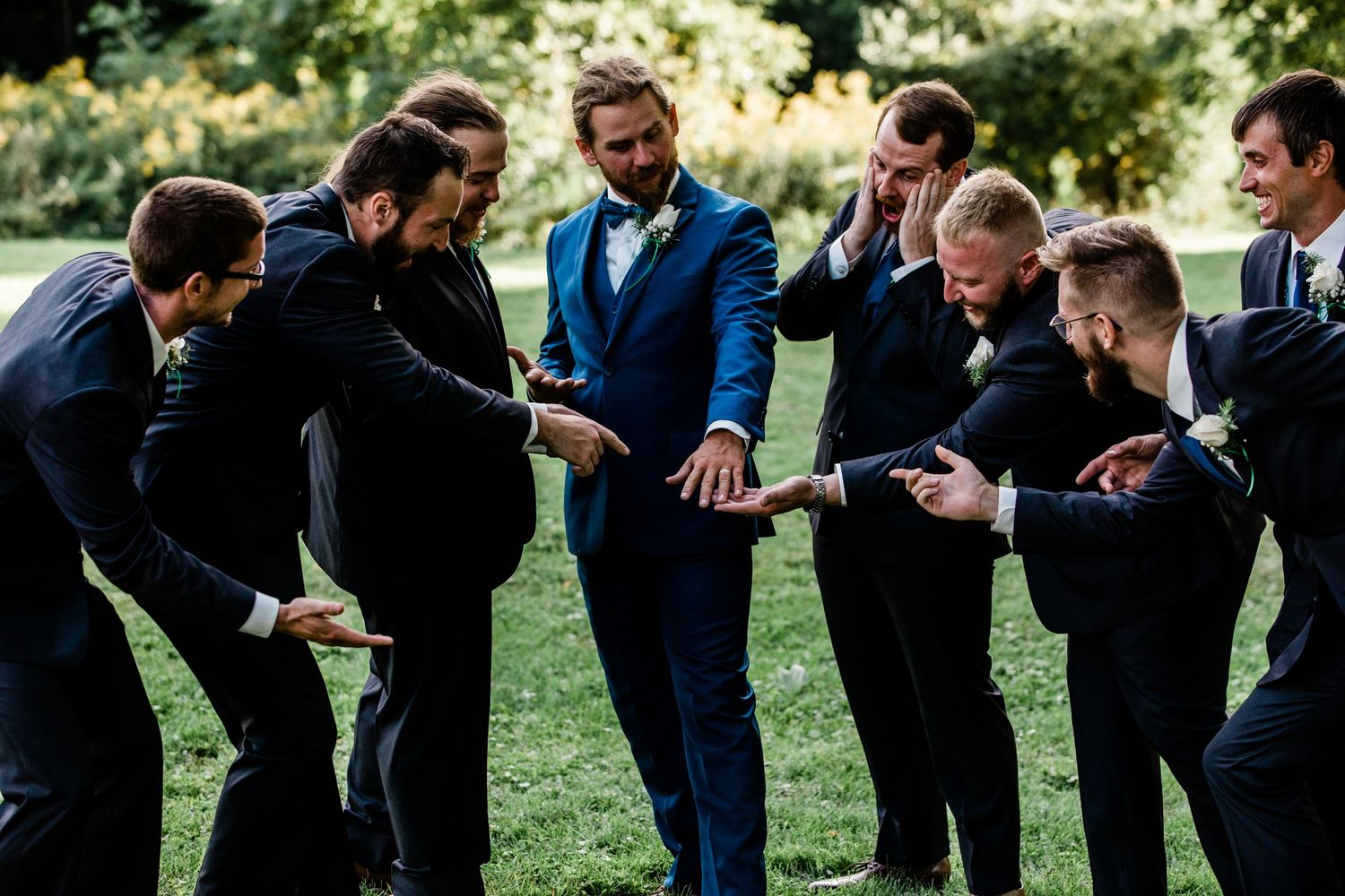 a group of groomsmen look at grooms ring adoringly.
