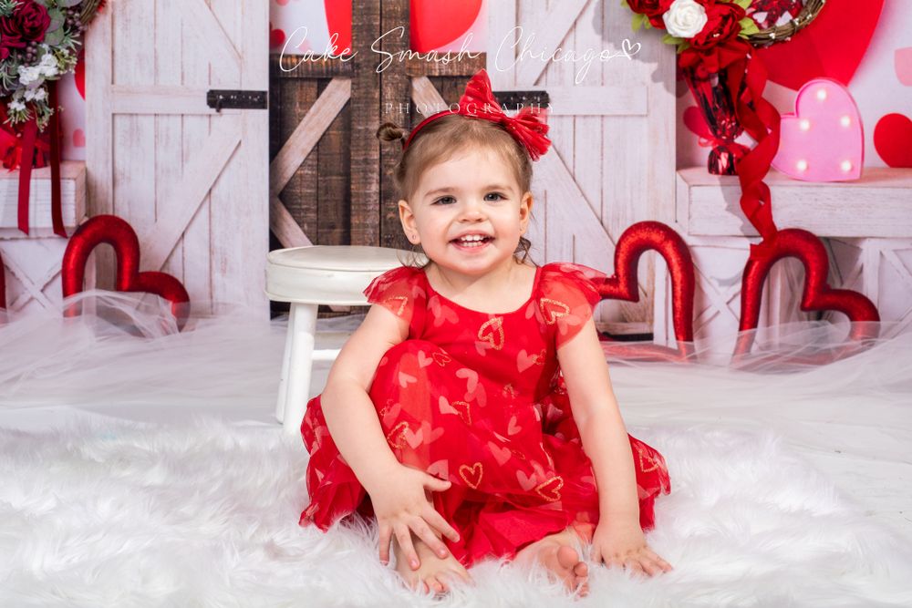 A smiling girl dressed in Valentine's Day-themed outfits posing for the camera during a Valentine's mini