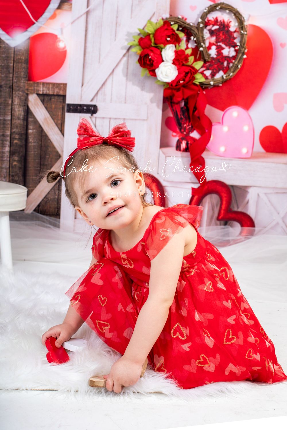 A smiling girl dressed in Valentine's Day-themed outfits posing for the camera during a Valentine's mini