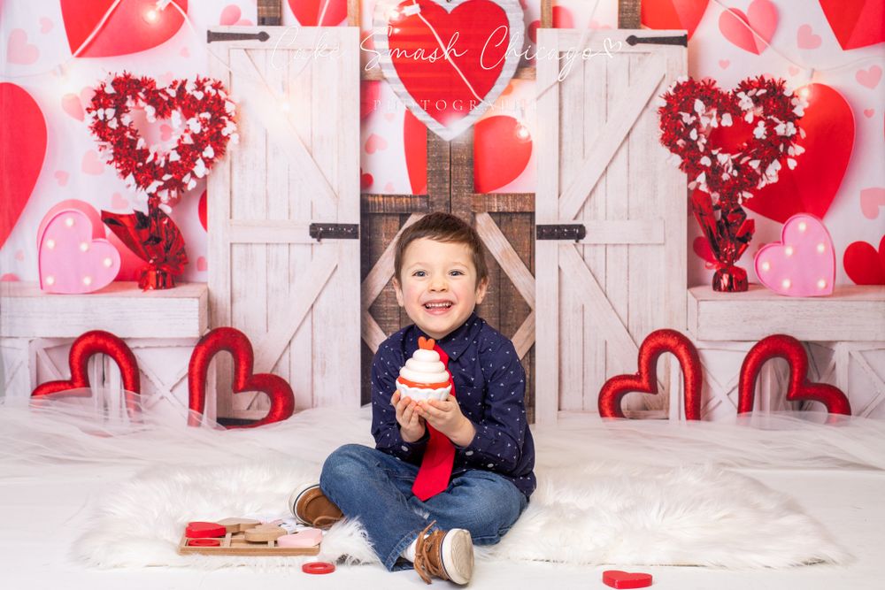 A smiling child dressed in Valentine's Day-themed outfits posing for the camera during a Valentine's mini