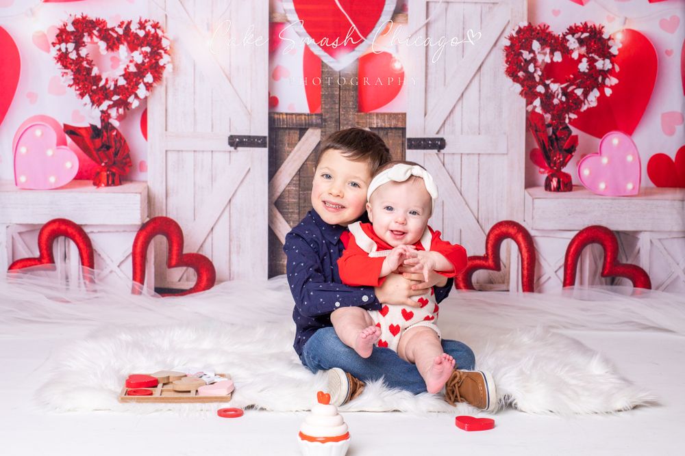A smiling child dressed in Valentine's Day-themed outfits posing for the camera during a Valentine's mini