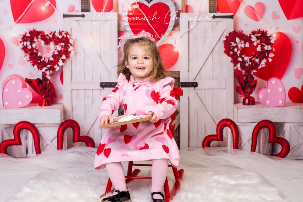 A smiling child dressed in Valentine's Day-themed outfits posing for the camera during a Valentine's mini