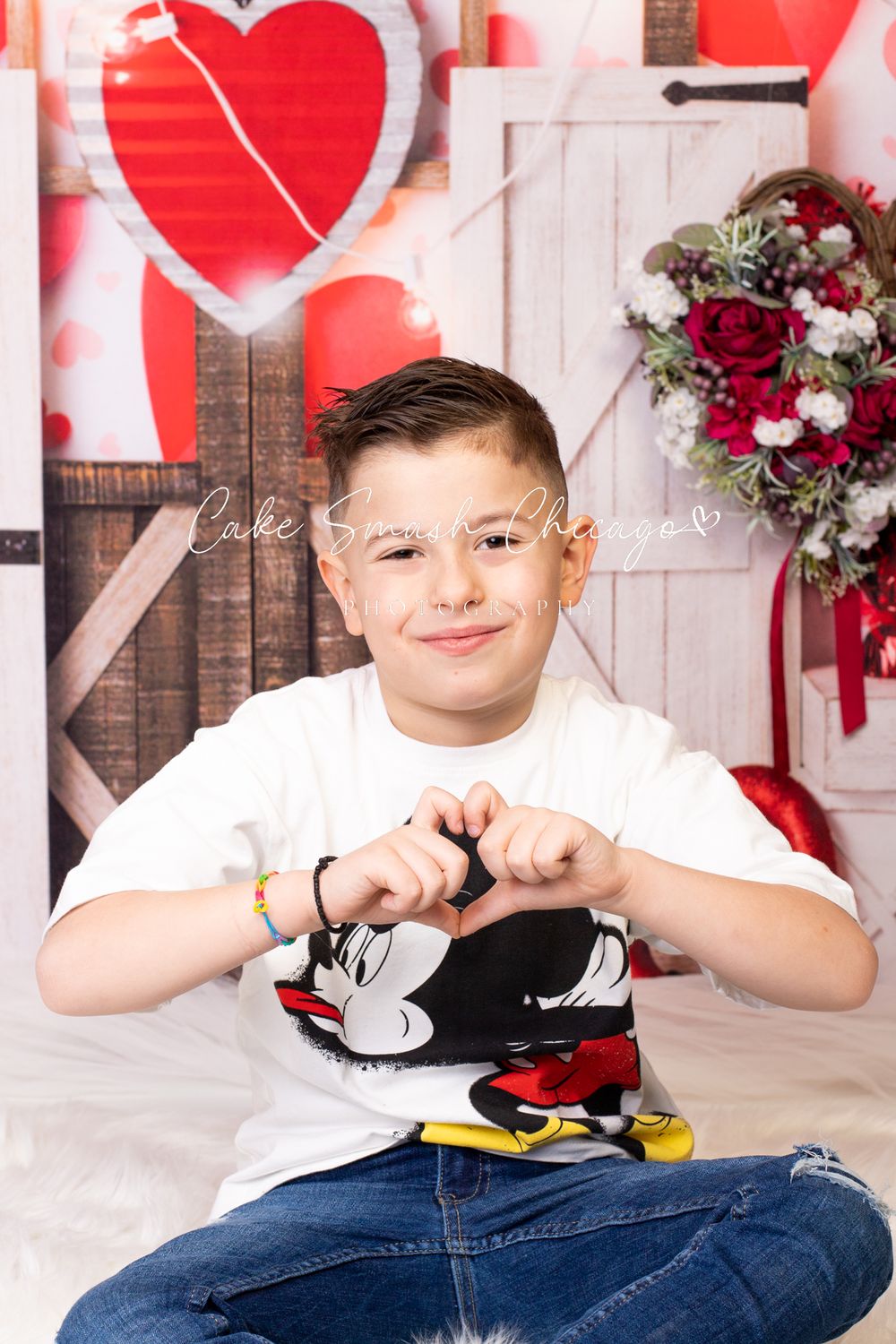 A smiling child dressed in Valentine's Day-themed outfits posing for the camera during a Valentine's mini