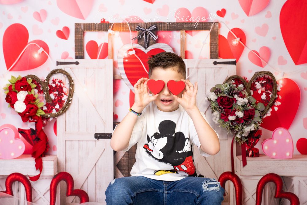A smiling child dressed in Valentine's Day-themed outfits posing for the camera during a Valentine's mini
