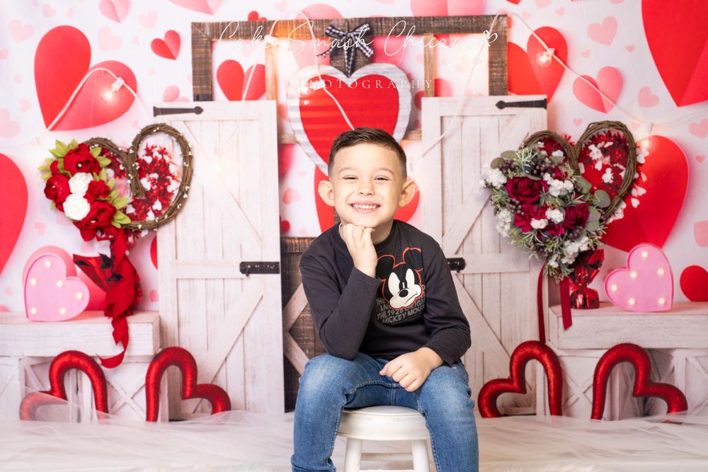 A smiling child dressed in Valentine's Day-themed outfits posing for the camera during a Valentine's mini