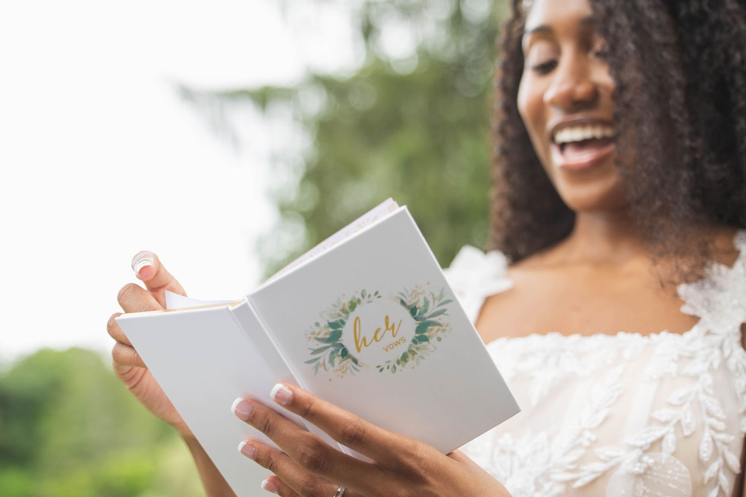 A close-up of a wedding vow book with floral design being held against a natural outdoor background.
