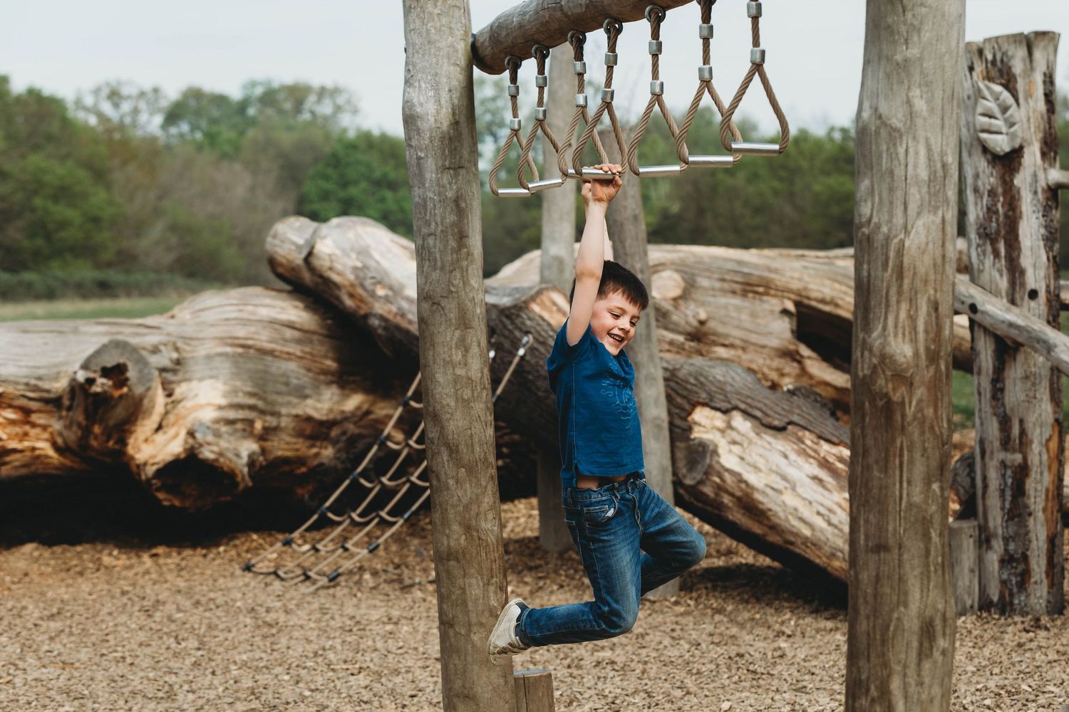 boy hanging off monkey bars in playground south weald country park