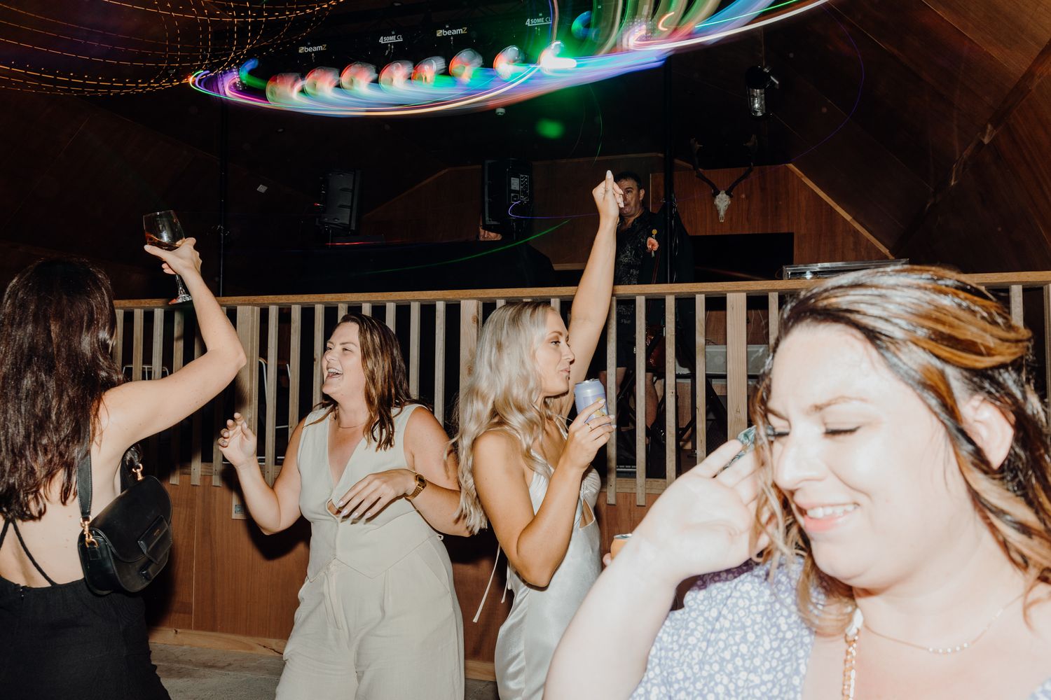 Wedding reception dance party with guests celebrating under neon ceiling lights.