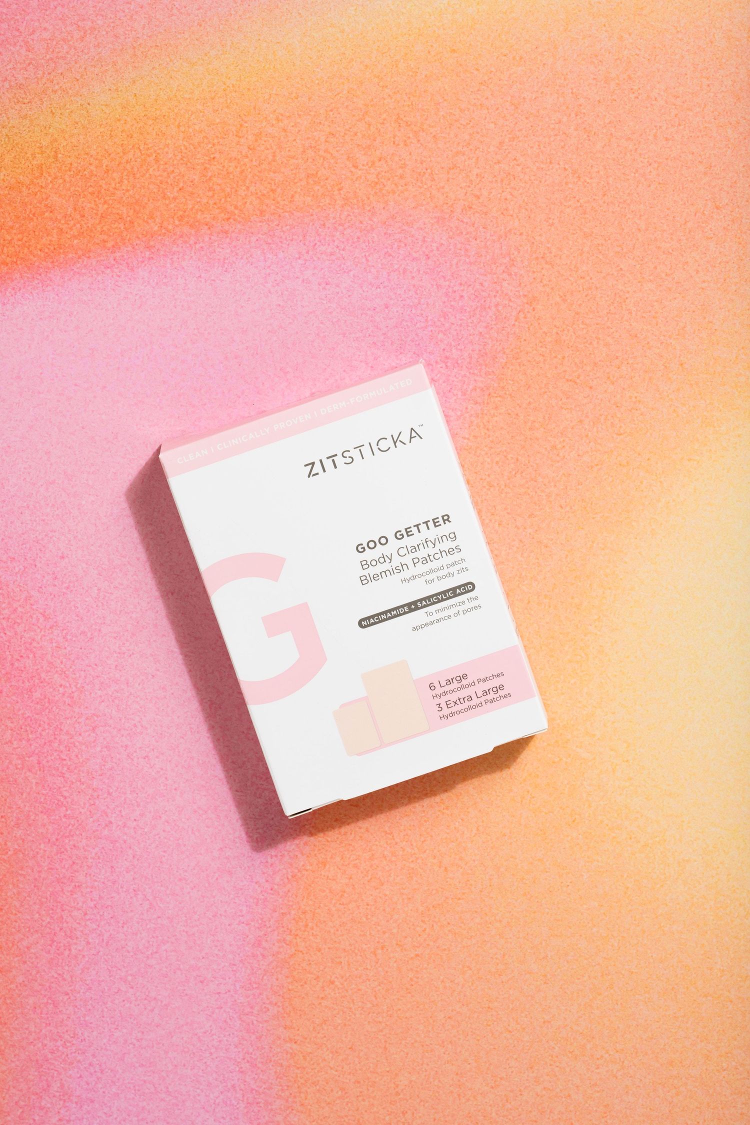 Single Zitsticka product box photographed against pink and orange gradient background.