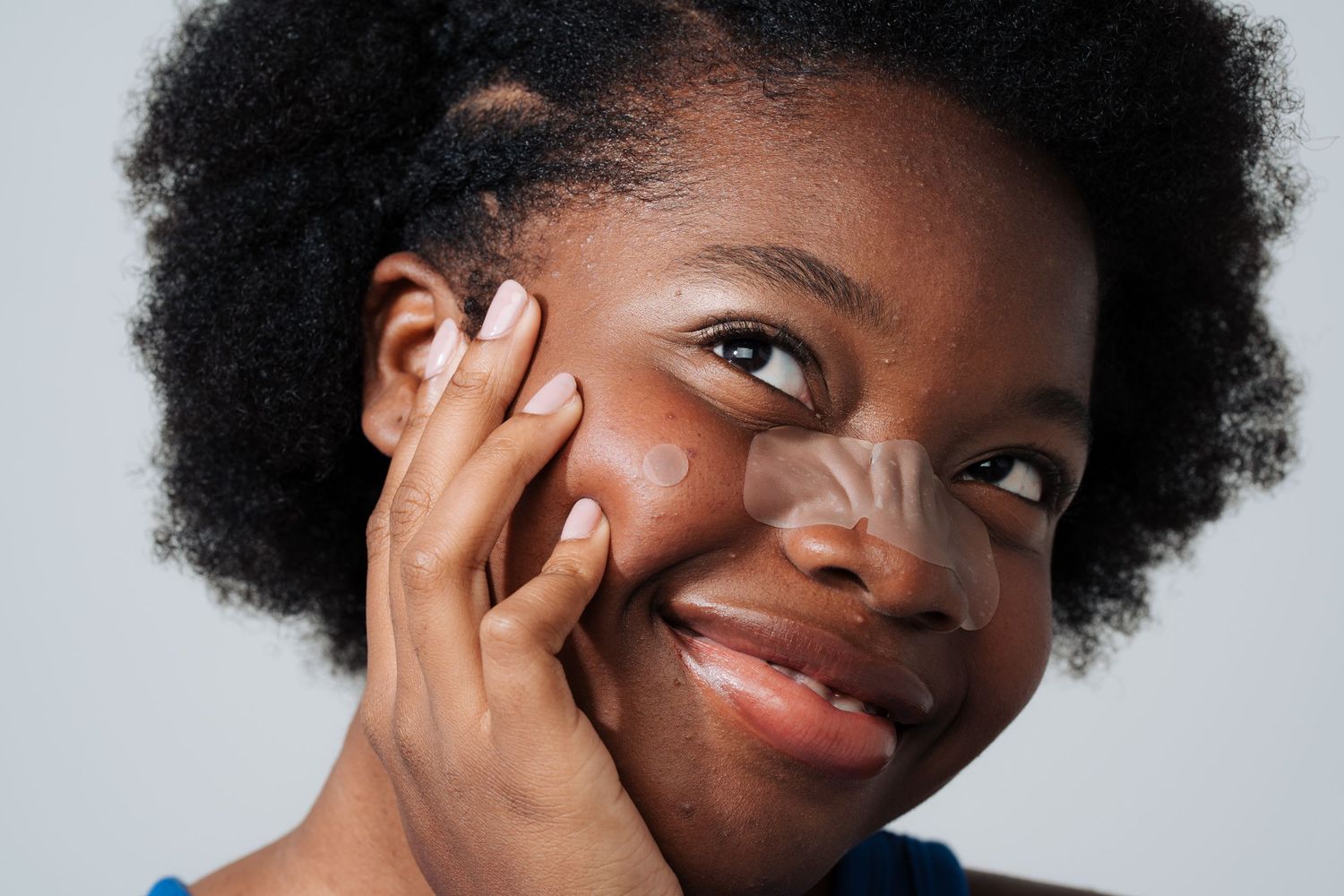 Close-up portrait with natural hair and bright smile against grey background.