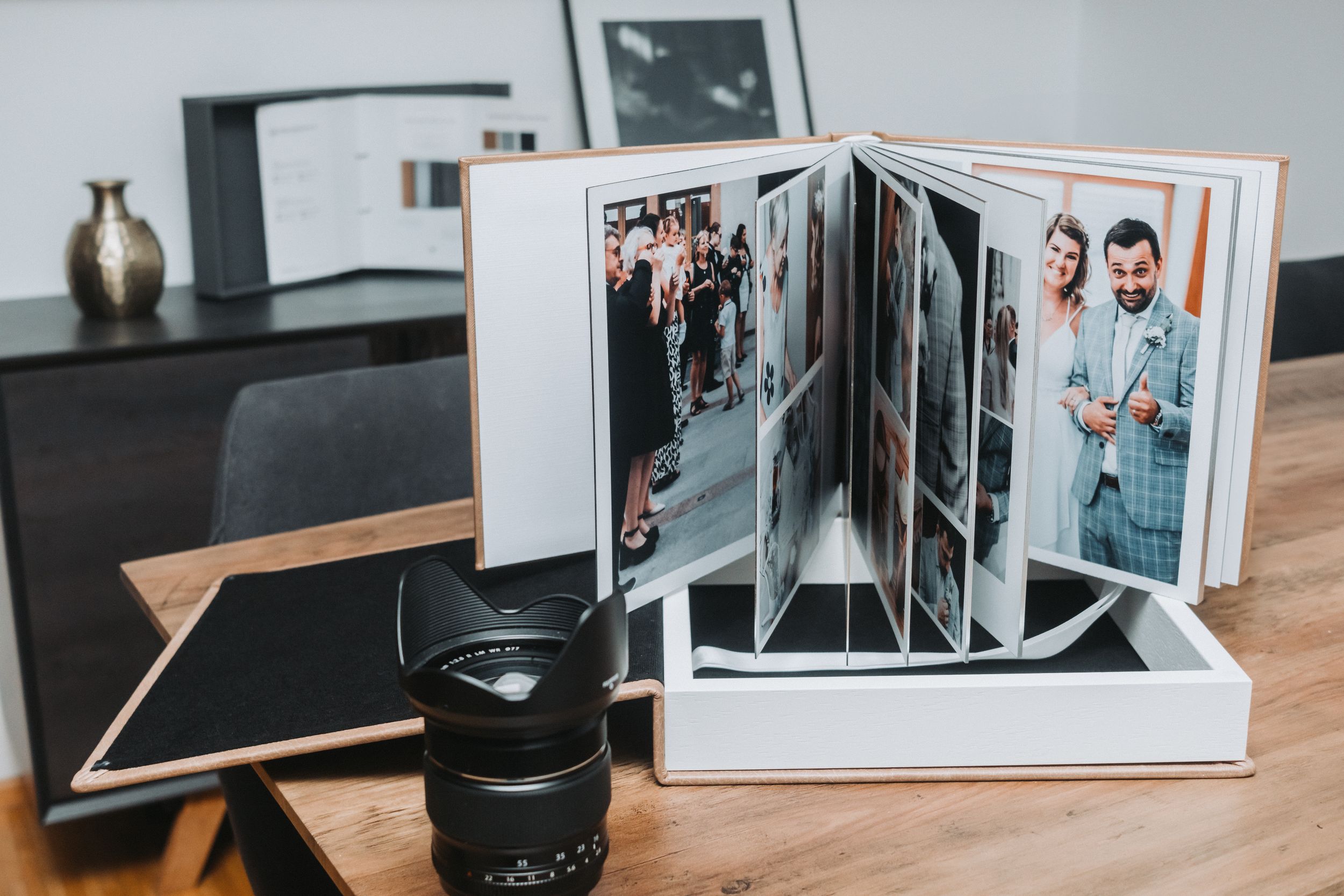 Professional wedding photo album display with camera lens and studio setup.
