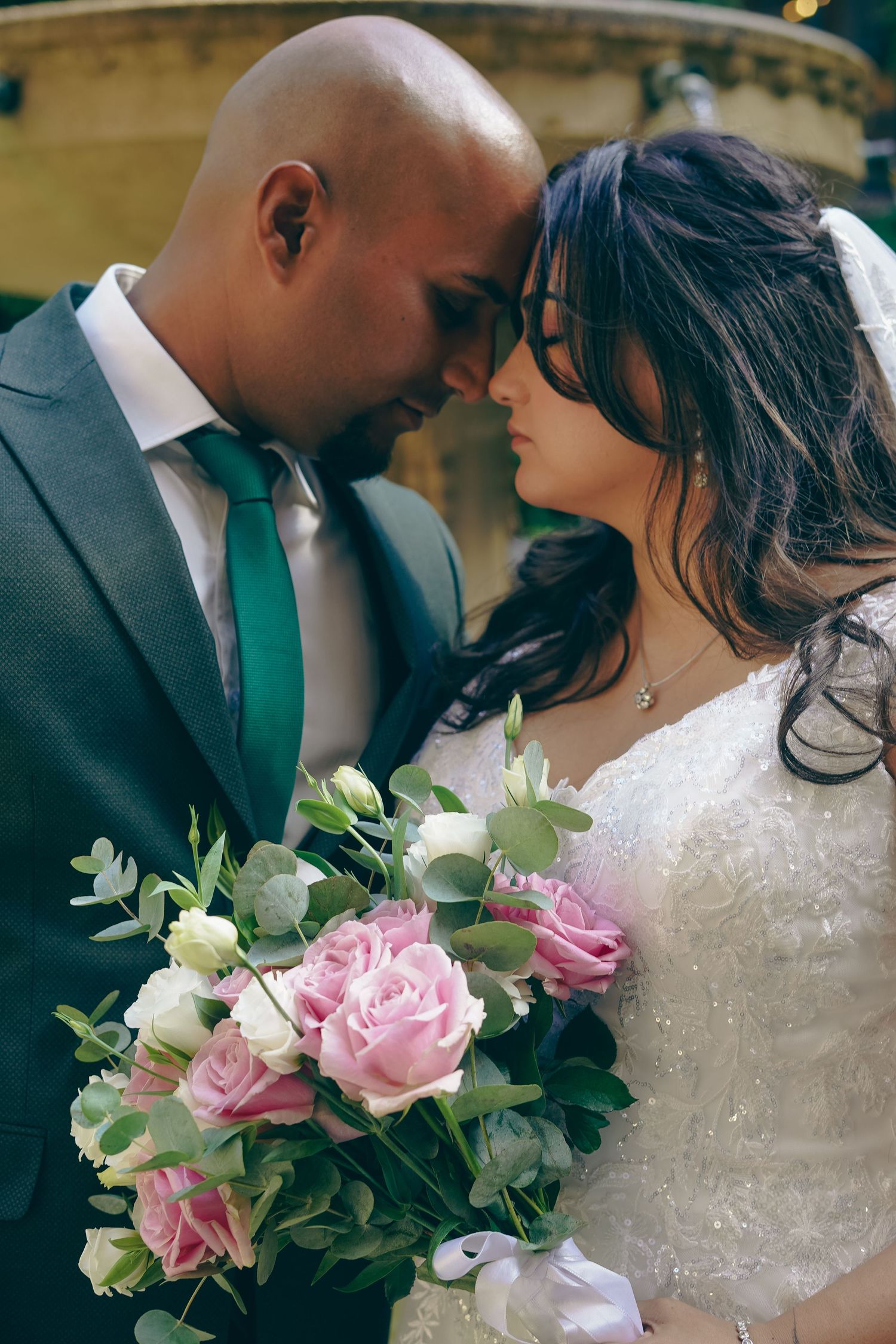 Romantic wedding portrait featuring pink and white rose bouquet against stone architecture.