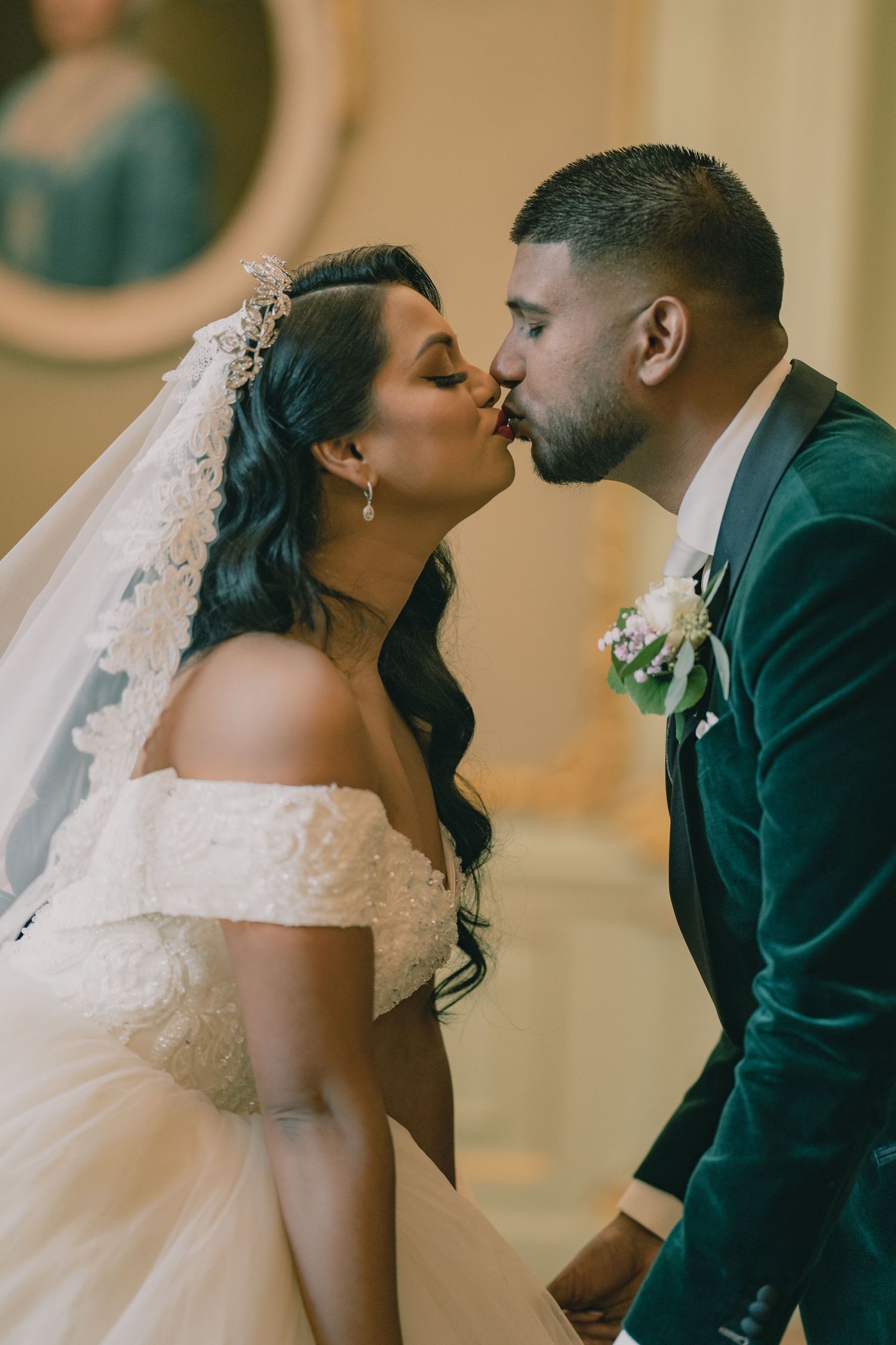 Romantic wedding moment captured in front of vintage mirror with bride in off-shoulder gown.