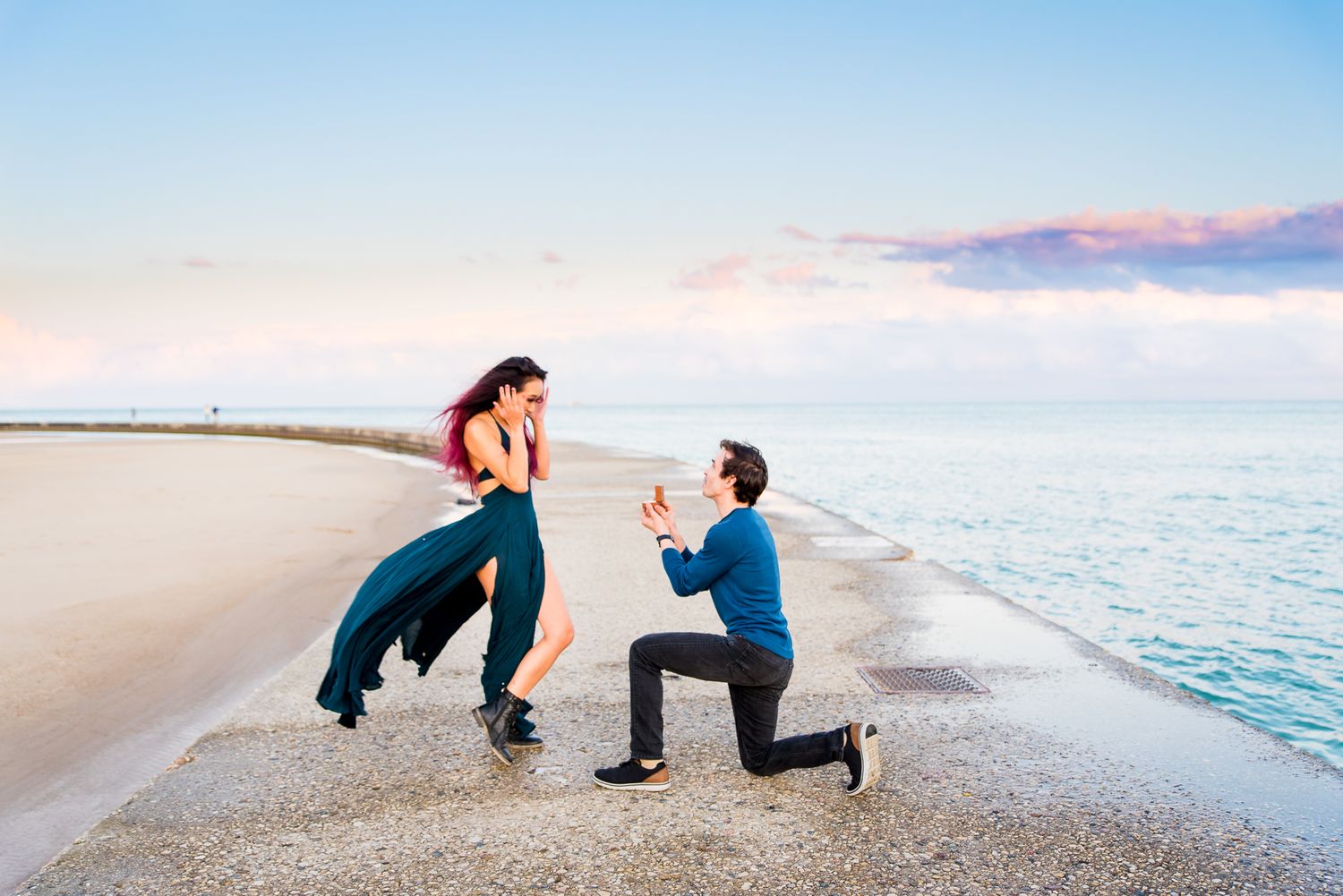 woman has hands on her face and is shocked to see boyfriend on one knee proposing