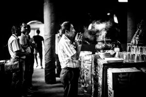 Black and white image of man praying at buddhist temple in Gloodok district of Jakarta Indonesia