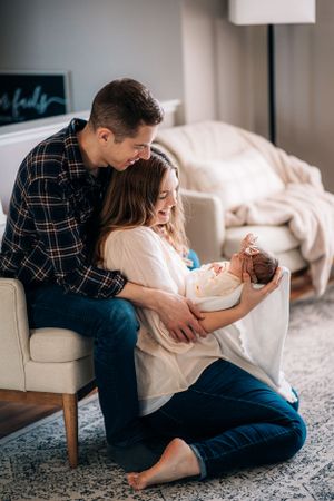 Family shares intimate moment with newborn baby in modern living room.